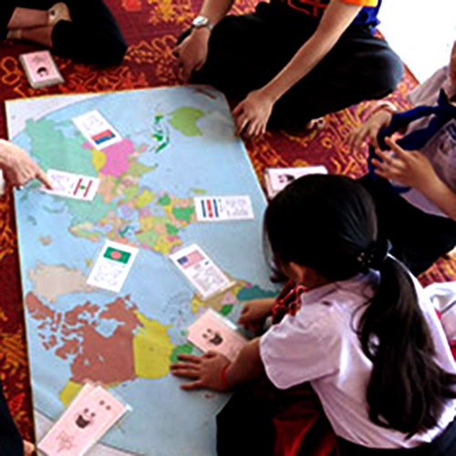 People in Laos playing a game with a large map, and cards showing each country.