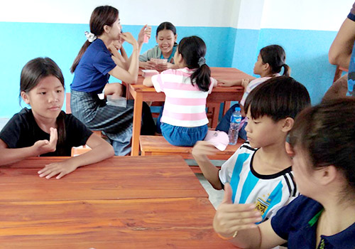 Schoolchildren learn hand signs for the Lao alphabet