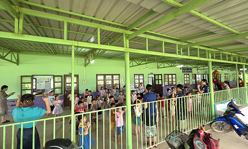 Children play in a shaded area outside a school