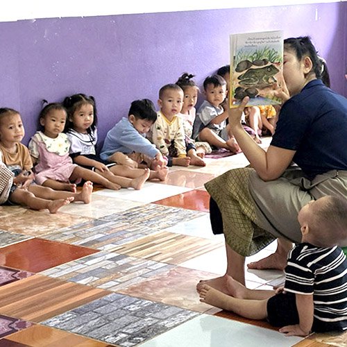 A teachers reads from a book, to preschools.