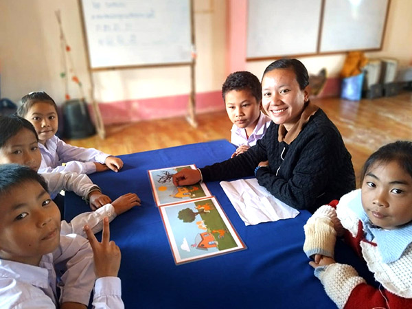 Pheuy Soneyaleum and several students sit at a table with Spot the Differences pictures in front of them.